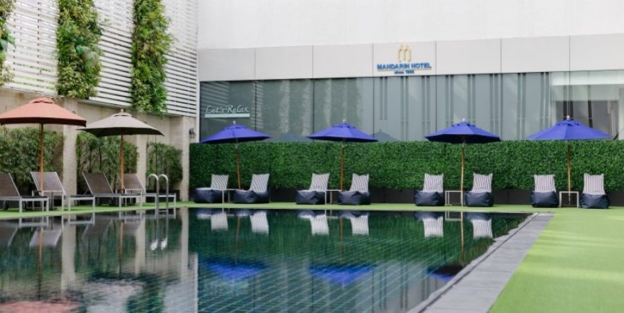 A view of the pool at the Mandarin Hotel Managed by Centre Point, with lounge chairs and umbrellas for relaxation.